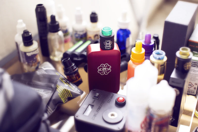 Vape mod surrounded by bottles of e-liquid